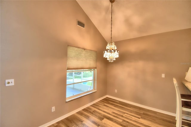 spare room featuring high vaulted ceiling, wood finished floors, visible vents, baseboards, and an inviting chandelier