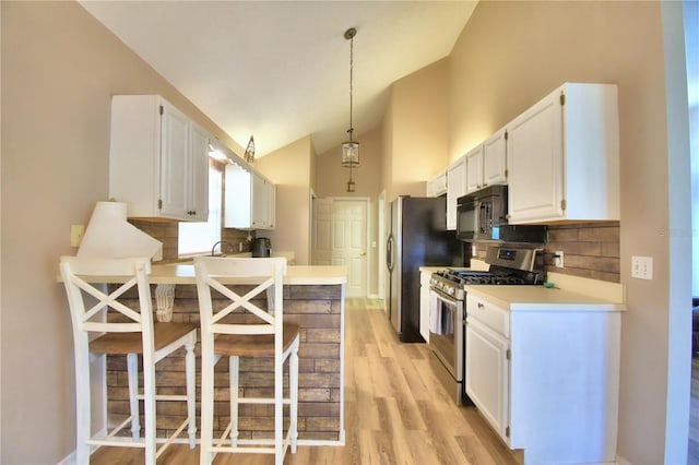 kitchen with light countertops, white cabinetry, black microwave, pendant lighting, and stainless steel range with gas stovetop