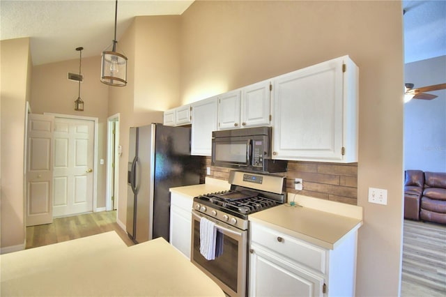 kitchen with white cabinets, gas range, light countertops, black microwave, and pendant lighting