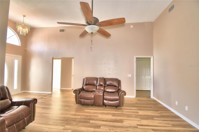 living area with baseboards, high vaulted ceiling, visible vents, and light wood-style floors