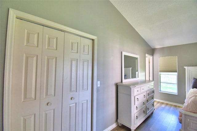 bedroom with lofted ceiling, a closet, baseboards, and wood finished floors