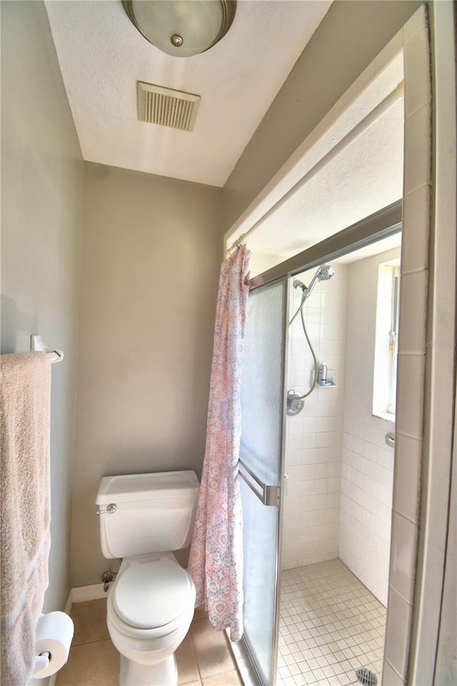 bathroom with a stall shower, visible vents, toilet, and tile patterned floors