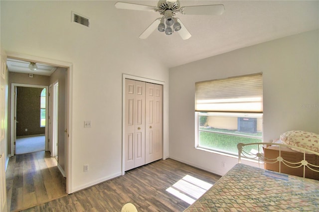 unfurnished bedroom featuring dark wood-style flooring, a closet, visible vents, vaulted ceiling, and baseboards