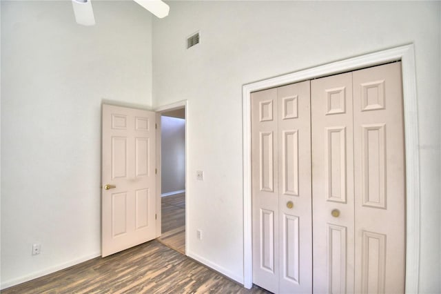 unfurnished bedroom with baseboards, visible vents, dark wood-type flooring, and a closet