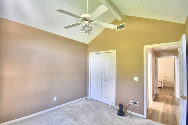 unfurnished bedroom featuring a textured ceiling, light colored carpet, visible vents, baseboards, and a closet