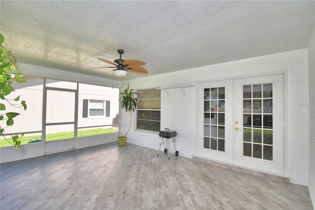 unfurnished sunroom featuring ceiling fan and french doors