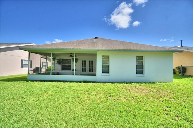 rear view of house featuring ceiling fan, a yard, and stucco siding