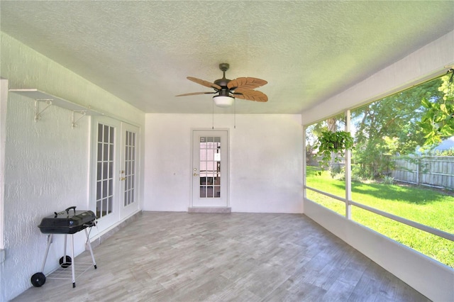 unfurnished sunroom with a ceiling fan and french doors