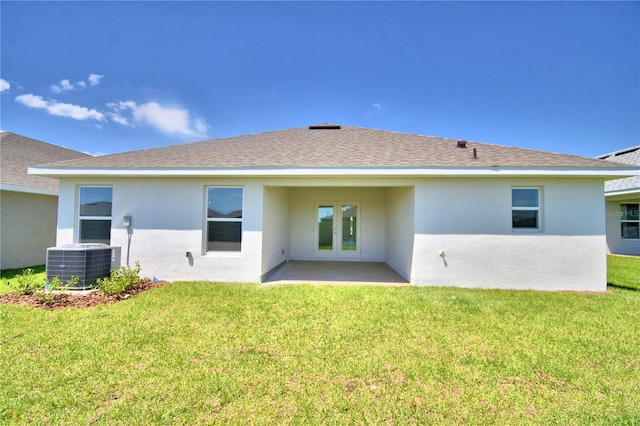 back of property with central air condition unit, a patio area, and a lawn