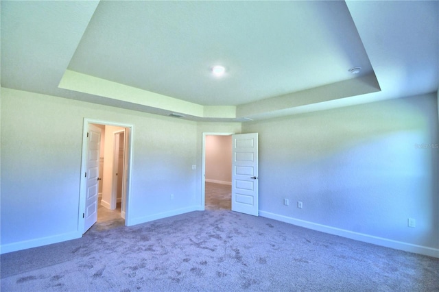 unfurnished bedroom with a raised ceiling and carpet floors