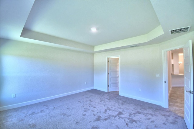 unfurnished room with carpet flooring and a raised ceiling