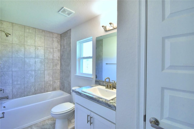 full bathroom featuring vanity, tiled shower / bath combo, and toilet