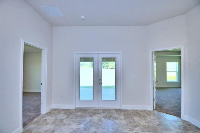 unfurnished room featuring plenty of natural light, light colored carpet, and french doors