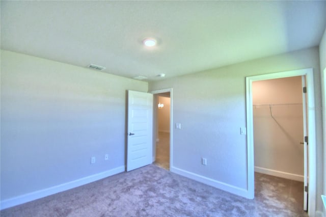 unfurnished bedroom with a spacious closet, a closet, and carpet floors