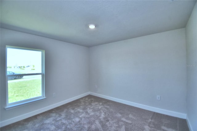 unfurnished room featuring dark colored carpet