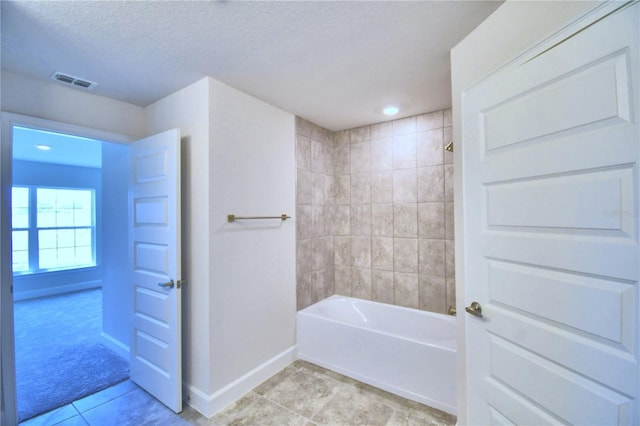 bathroom featuring tile patterned flooring, washtub / shower combination, and a textured ceiling