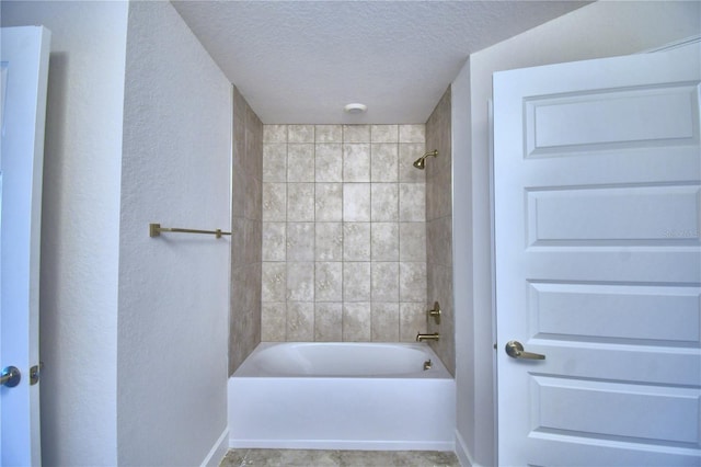 bathroom featuring a textured ceiling and tiled shower / bath