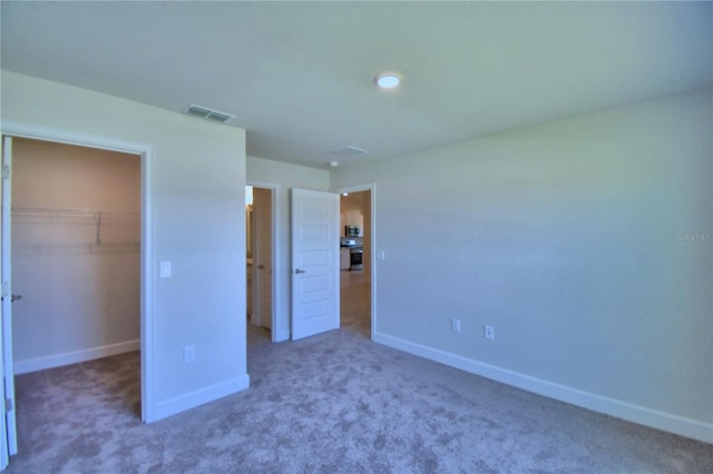 unfurnished bedroom featuring carpet, a walk in closet, and a closet