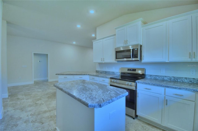 kitchen with light stone countertops, a center island, stainless steel appliances, vaulted ceiling, and white cabinets