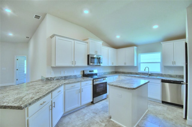 kitchen with white cabinetry, sink, light stone counters, a kitchen island, and appliances with stainless steel finishes