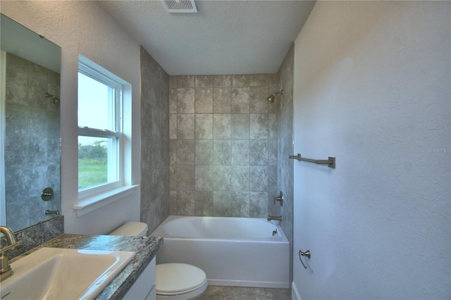 full bathroom with vanity, a textured ceiling, toilet, and tiled shower / bath combo