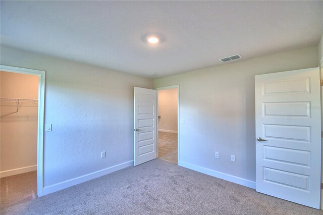 unfurnished bedroom with a spacious closet, carpet floors, and a closet