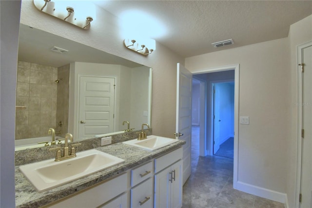 bathroom featuring vanity, a textured ceiling, and tiled shower / bath