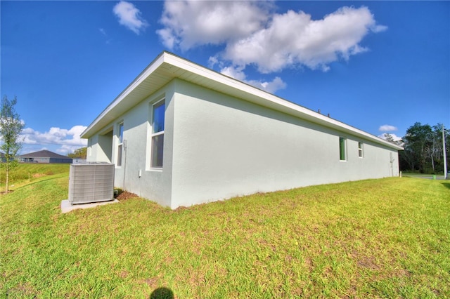 view of side of property featuring a lawn and central air condition unit