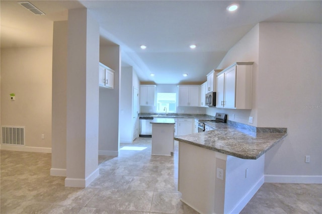 kitchen with sink, kitchen peninsula, a kitchen bar, white cabinets, and appliances with stainless steel finishes