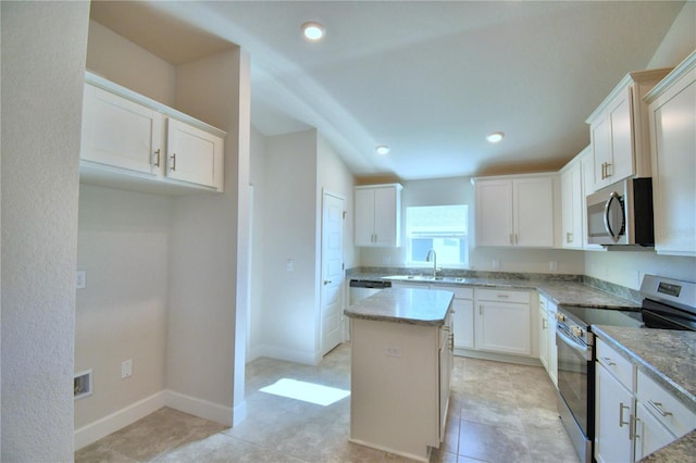 kitchen featuring lofted ceiling, white cabinets, light stone countertops, a kitchen island, and stainless steel appliances