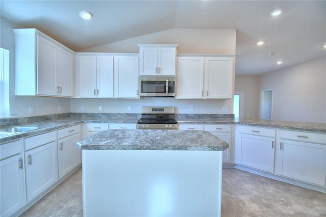 kitchen featuring appliances with stainless steel finishes, vaulted ceiling, sink, white cabinets, and a kitchen island