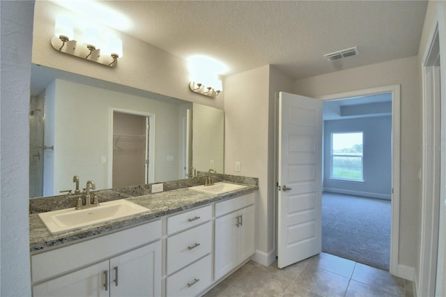 bathroom featuring tile patterned flooring, vanity, and a textured ceiling