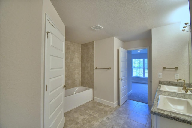 bathroom with vanity, a textured ceiling, a tub to relax in, and tile patterned flooring