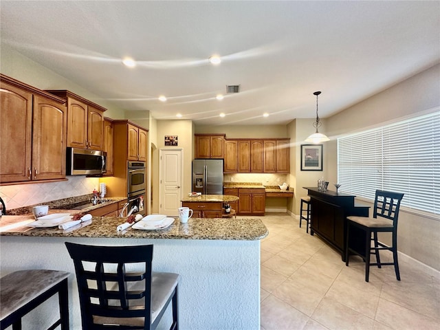 kitchen featuring a breakfast bar, appliances with stainless steel finishes, a center island, and light stone countertops