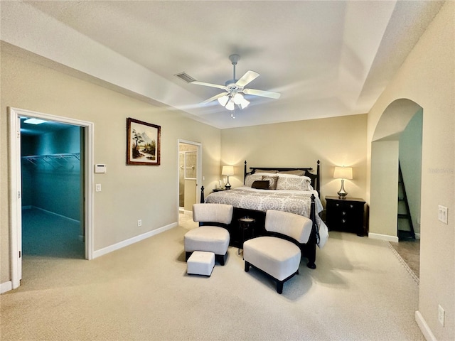 bedroom with a walk in closet, ceiling fan, a closet, and light colored carpet