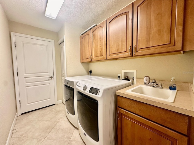 washroom with cabinets, a textured ceiling, sink, light tile patterned floors, and separate washer and dryer