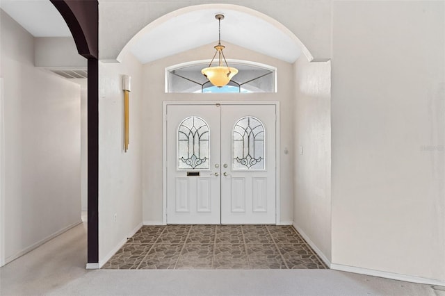 carpeted entryway featuring vaulted ceiling