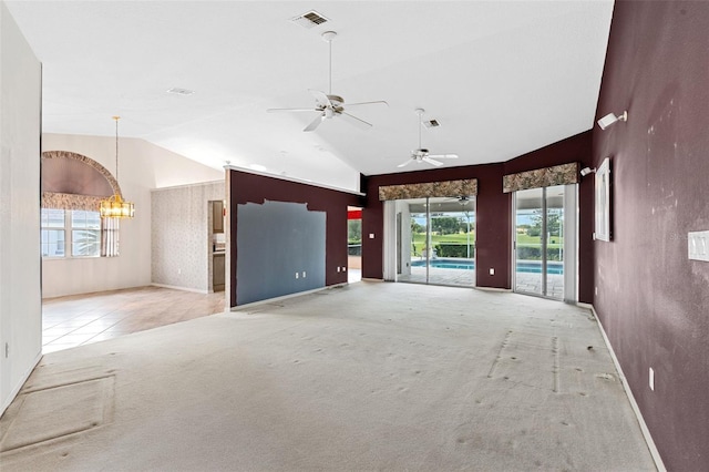 unfurnished living room featuring a wealth of natural light, high vaulted ceiling, light carpet, and ceiling fan with notable chandelier