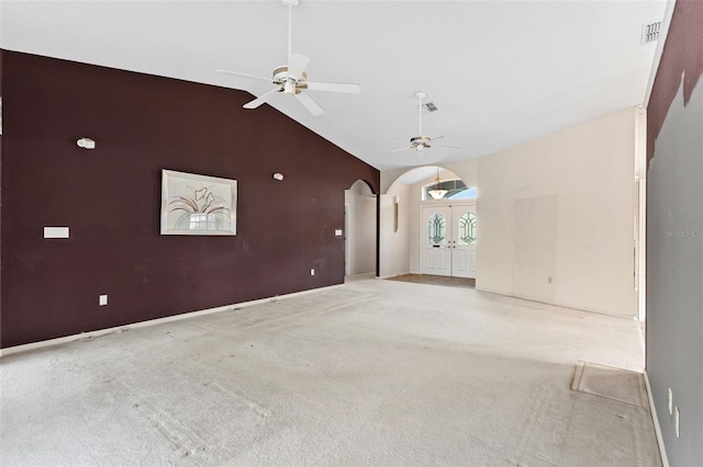 unfurnished living room featuring ceiling fan, french doors, high vaulted ceiling, and light colored carpet