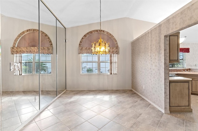 unfurnished dining area with light tile patterned floors, an inviting chandelier, lofted ceiling, and sink