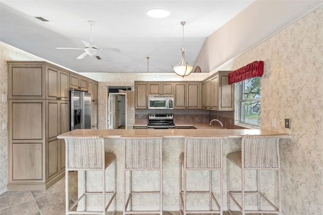 kitchen featuring a kitchen bar, kitchen peninsula, stainless steel appliances, and lofted ceiling