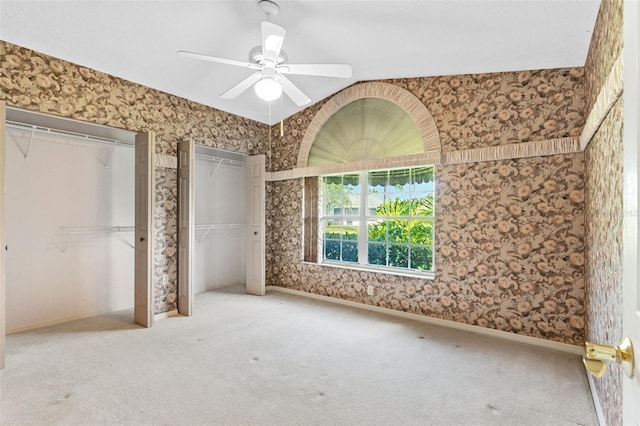 unfurnished bedroom featuring carpet flooring, multiple closets, and ceiling fan