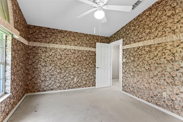 empty room featuring carpet floors, vaulted ceiling, a wealth of natural light, and ceiling fan