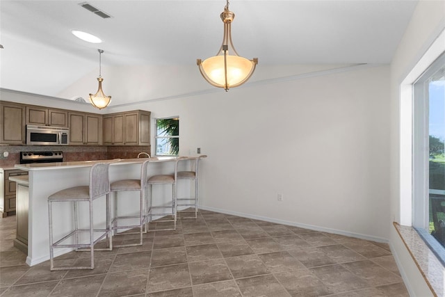 kitchen with lofted ceiling, stainless steel appliances, a kitchen bar, and decorative light fixtures