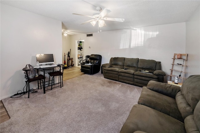 living room with ceiling fan, light colored carpet, and a textured ceiling