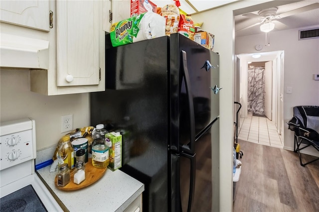 kitchen featuring ceiling fan, black refrigerator, stove, and light hardwood / wood-style floors