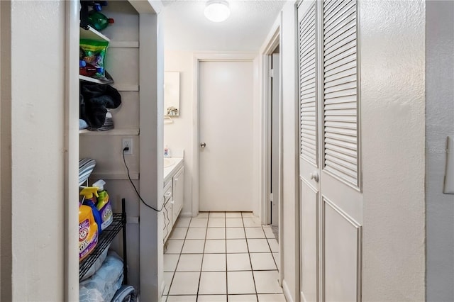 clothes washing area with washing machine and dryer, light tile patterned flooring, and a textured ceiling