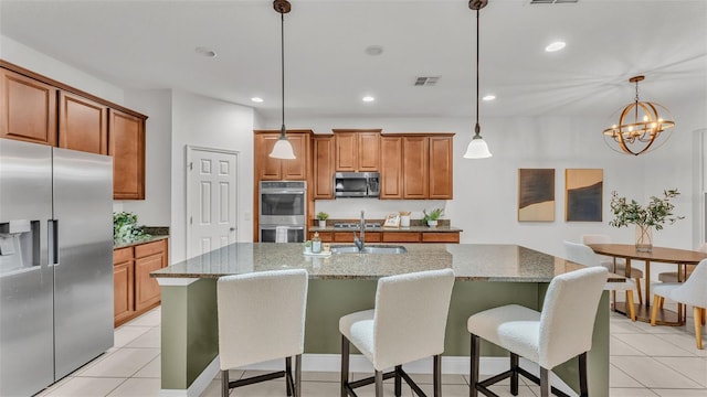 kitchen with a center island with sink, decorative light fixtures, stone countertops, and stainless steel appliances