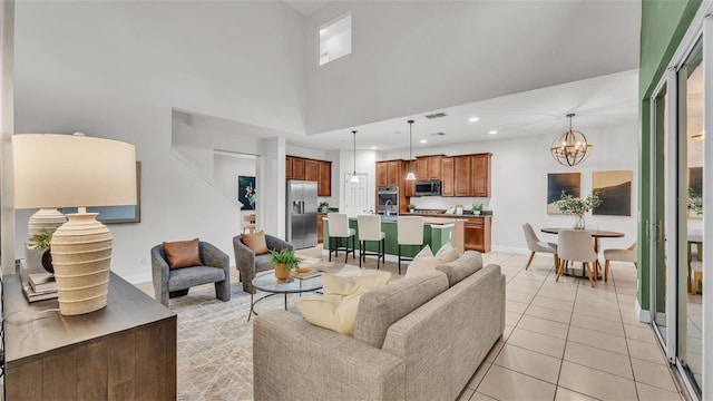 living room featuring light tile patterned flooring, a high ceiling, and a notable chandelier