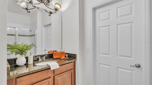 bathroom with a notable chandelier, a shower with door, and vanity